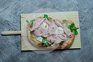 Roman pinsa, variant of the classic Italian pizza topped with mortadella, stracciatella and lamb\'s lettuce and pistachios