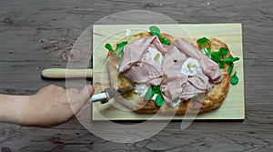 Roman pinsa, variant of the classic Italian pizza topped with mortadella, stracciatella and lamb's lettuce and pistachios