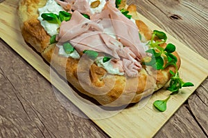 Roman pinsa, variant of the classic Italian pizza topped with mortadella, stracciatella and lamb\'s lettuce and pistachios