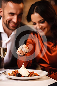 Romance and dating concept. Young couple man and woman celebrating and eating delicious dessert in restaurant. Two