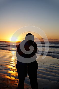Romance at daybreak. Silhouette image of a couple hugging and kissing at sunrise.