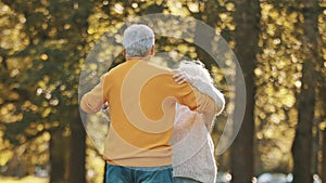 Romance at old age. Elderly retired couple dancing in the park in autumn