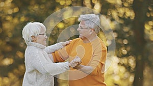 Romance at old age. Elderly retired couple dancing in the park in autumn