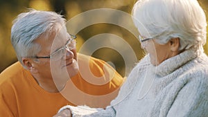 Romance at old age. Retired couple enjoying autumn picnick. Lying on the blanket and looking at each other