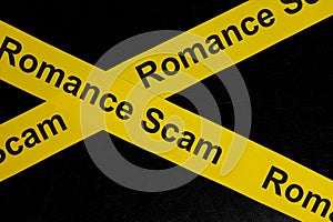 Romance scam alert, caution and warning concept. Yellow barricade tape with word in dark black background.