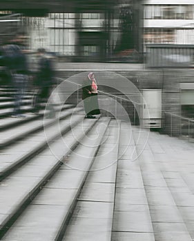 Romani woman standing in a blurred vision of city life.