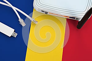 Romania flag depicted on table with internet rj45 cable, wireless usb wifi adapter and router. Internet connection concept