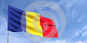 Romania flag on flagpole on blue sky background. Romanian flag waving in wind on a background of sky with white clouds. Place for