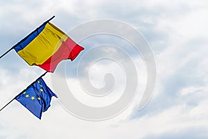 Romanian flag and European Union flag waving in high winds, with stormy clouds in the background, in Sibiu, Romania - copy space
