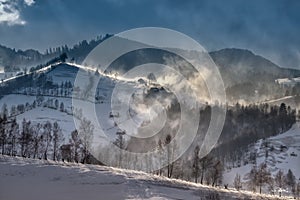 Romanian hillside and village in winter time , mountain landscape of Transylvania in Romania