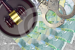 1 Romanian leu bills and judge hammer with police handcuffs on court desk. Concept of judicial trial or bribery. Tax avoidance photo