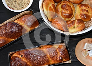 Romanian traditional Cozonac sweet bread in trays on a wooden black table with Turkish delight, nuts and bun bread in a