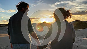 Romantic adult mature couple in love enjoying together an amazing outdoors sunset holding hands and looking each other. Family in