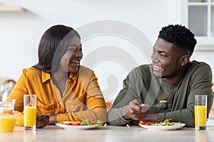 Romantic african american couple eating tasty breakfast together in kitchen at home