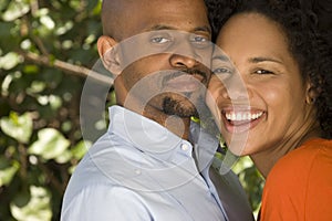 Romantic African American couple hugging outside.