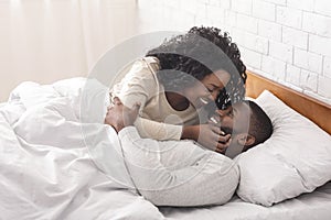 Romantic african couple kissing in bed, enjoying spending time together