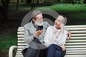 Romantic aged couple sitting on wooden bench at green park