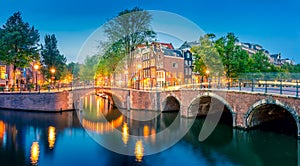 Romantic Amsterdam lit the lights. Evening panoramic view of the famous historic center with lantern lights, bridges, canals and