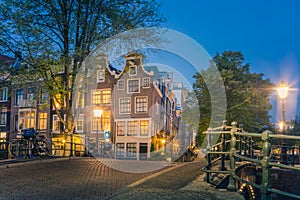 Romantic Amsterdam lit the lights. Evening view of the famous historic center with lantern lights, bridges, canals and cute Dutch