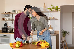 Romantic arab spouses bonding, preparing meal together, loving husband and wife cooking, kitchen interior, copy space