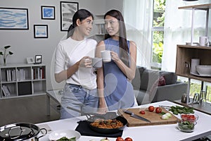 Romantic Asian lesbian couple is cooking on kitchen. LGBT lesbian couple are having fun together while preparing healthy food