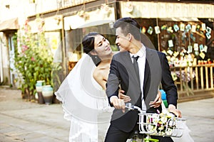 Romantic asian newly-wed riding a bicycle photo