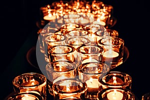Romantic atmosphere, many small, lit candles on the table. Dark background