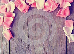 Romantic background - rustic wooden table with pink rose petals
