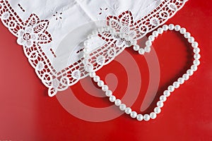 Romantic background for valentine`s day with pearl necklace heart and lace on red background