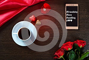 Romantic background with wedding ring, rose flowers, smartphone, cup of coffee and chocolate candy
