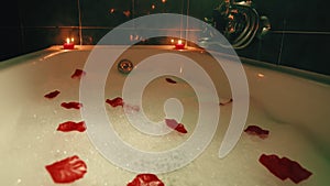 Romantic bathtub with flower petals and red candles