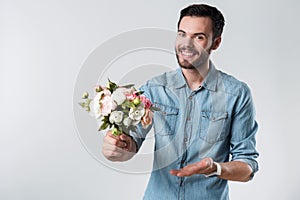 Romantic bearded man smiling and holding a bunch of flowers.