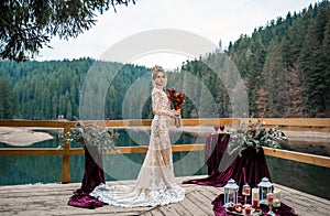 Romantic beautiful bride in luxury dress posing on the lake.