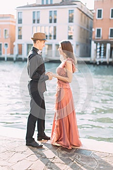 Romantic beautiful couple in Venice happy together standing on the background of venetian canal and buildings. Italy, Europe.