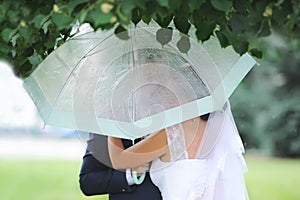 Romantic beautiful wedding couple hugging under elegant umbrella.