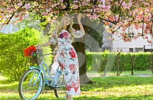 Romantic bike ride. Girl long dress retro cruiser bicycle sakura tree. Spring holidays. Tourism concept. Transportation
