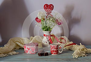 Romantic bouquet of tulips and box with a gift in the shape of heart, candies and a cup of coffee