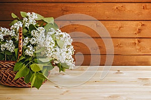 Romantic bouquet of white lilac in wicker basket on wooden table. Selective focus.