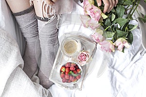 Romantic breakfast in bed. A bouquet of roses and a fragrant morning coffee. Fresh strawberries. Good morning, in the crumpled bed