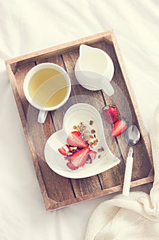 Romantic breakfast in bed. Yogurt with granola and strawberry i