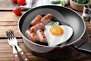 Romantic breakfast with fried sausages and heart shaped egg on wooden table. Valentine`s day celebration