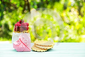 Romantic breakfast. A glass with yogurt and raspberries. Pink heart of origami. Copy space