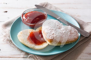 Romantic breakfast heart-shaped bun and berry jam on white wooden table