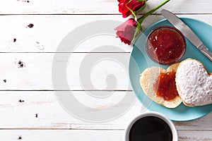 Romantic breakfast with heart-shaped bun,coffee, berry jam and roses