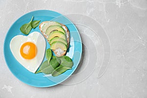 Romantic breakfast with heart shaped egg on light grey table, top view. Space for text