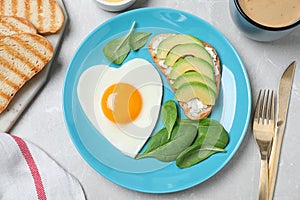 Romantic breakfast with heart shaped fried egg served on grey table, flat lay