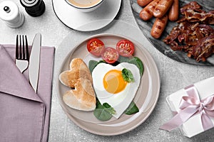 Romantic breakfast with heart shaped toasts and fried egg on grey table, flat lay. Valentine`s day celebration