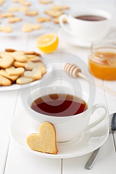 Romantic breakfast for lovers on Valentines day: two cups of tea and heart shaped cookies on white wooden table.