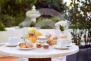 A romantic Breakfast is served on the terrace. Fresh fruit, pastries, jam and coffee are on the table in the fresh air decorated