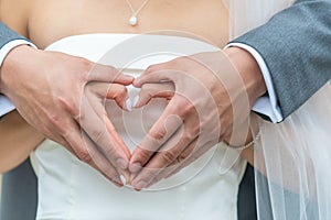 Romantic bride and groom showing a heart symbol with hands